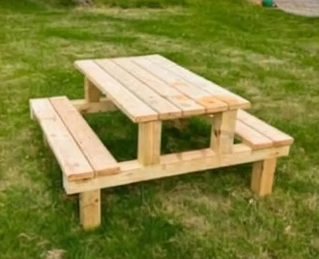 Wooden picnic table with attached benches on a lawn